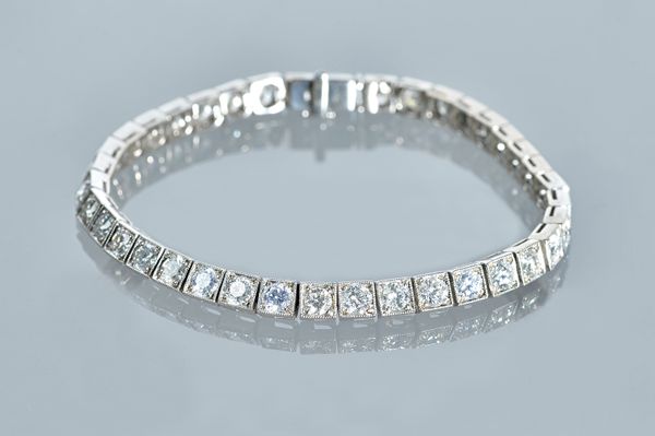 A white precious metal and diamond set tennis bracelet, set with thirty-eight circular cut diamonds, claw set in square links, to a box and tongue cla