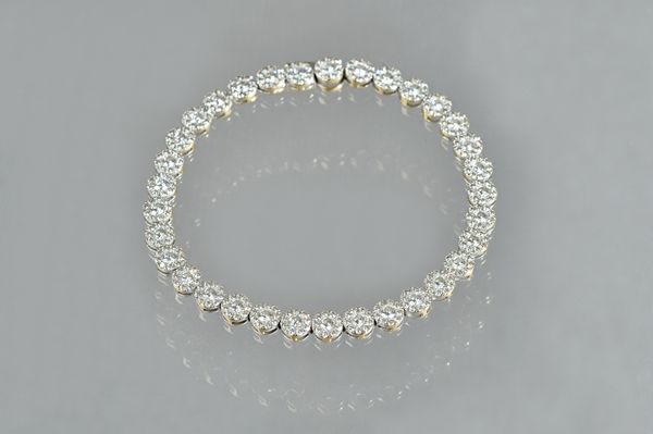 An 18ct white gold and diamond set tennis bracelet, set with thirty-three circular cut diamond set cluster links, to a box and tongue clasp detailed 1