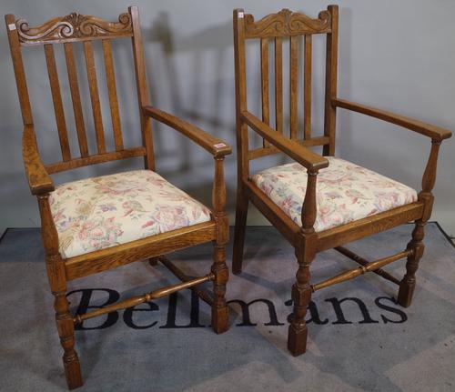 A pair of mid-20th century oak open armchairs with stick backs on block end turned supports, 57cm wide x 105cm high.