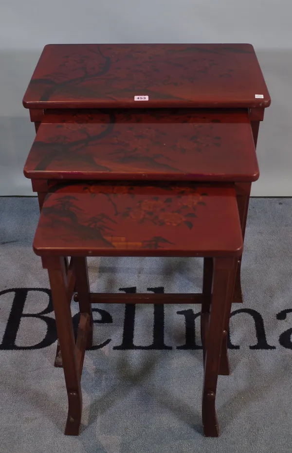 A 20th century nest of three red lacquer occasional tables, the largest 57cm wide x 66cm high.