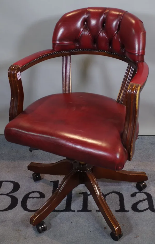 A 20th century stained beech office swivel open armchair with red leather button back upholstery, 58cm wide x 92cm high.