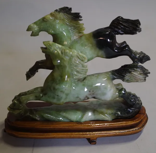 A 20th century Chinese hardstone figure of two horses on a hardwood stand.