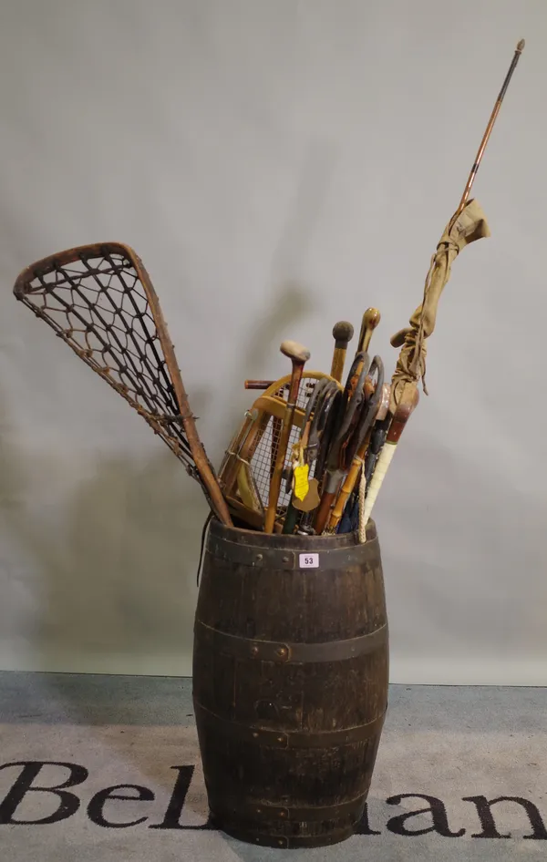 A 19th century oak and iron bound coopered barrel containing various walking sticks and umbrellas and sporting equipment.
