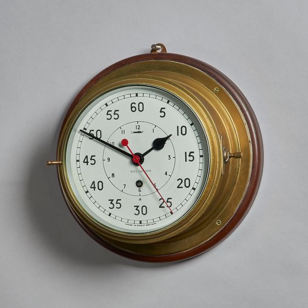 A ship's brass capstan timepieceWith white-painted dial, sweep centre seconds and Admiralty arrow, bevelled glazed bezel, drum-shaped case, with mahog