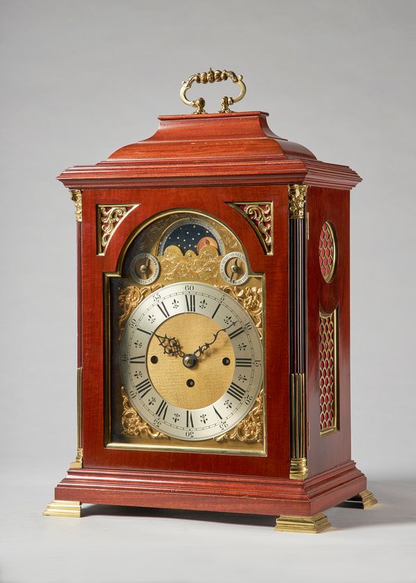 An Edwardian giltmetal-mounted mahogany three train quarter chiming bracket clockThe ogee case with brass carrying handle surmount, above a glazed pan