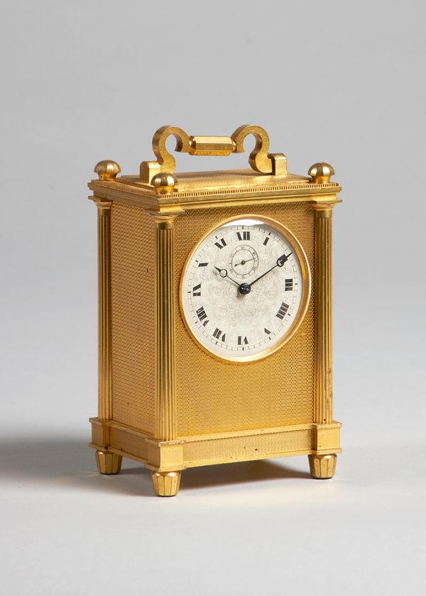 An English giltmetal carriage timepieceCirca 1870The rectangular case with shaped handle and four faceted finials, with engine-turned panels to the to