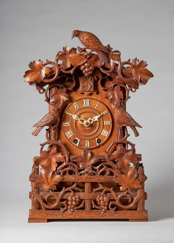 A Tyrolean carved walnut striking fusée cuckoo mantel clockBy Aron Ketterer, Furtwangen, late 19th centuryIn an architectural case carved with foliage