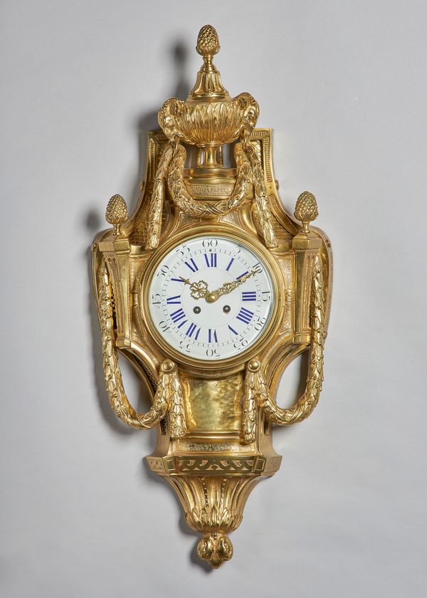 A French giltmetal Cartel clockIn the Louis XVI style, circa 1900Surmounted by a berried finial and urn with ram's mask and laurel festoons, the shape