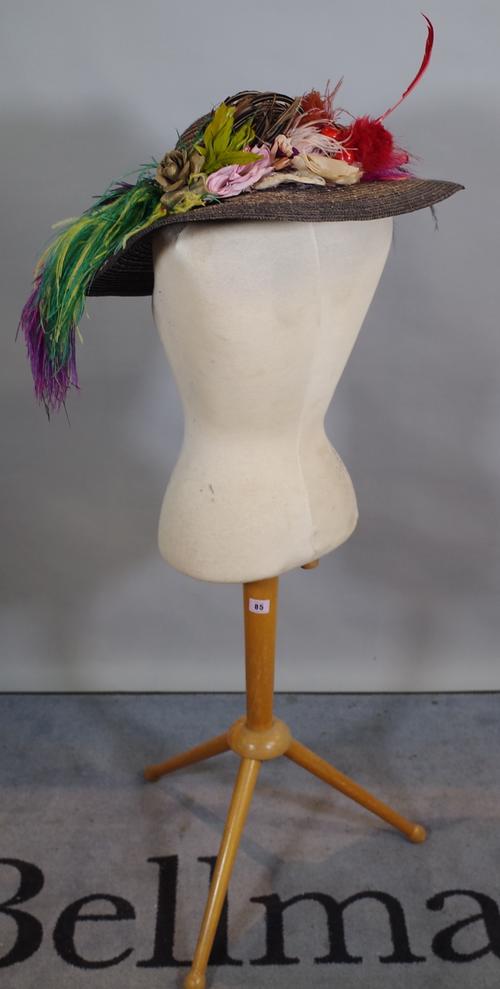 A 20th century tailor's dummy on beech tripod base, together with a colourful ladies hat.