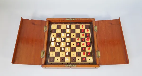 An early 20th century mahogany cased travelling chess set with stained bone pieces, king 1.8cm high, board 25cm wide.