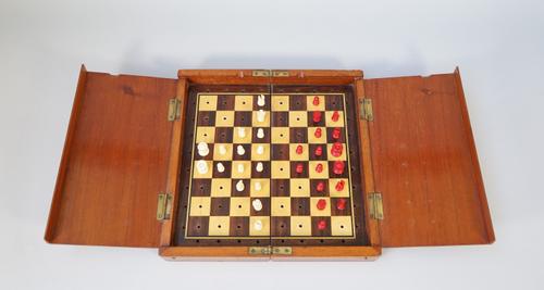 An early 20th century mahogany cased travelling chess set with stained bone pieces, king 1.8cm high, board 25cm wide.