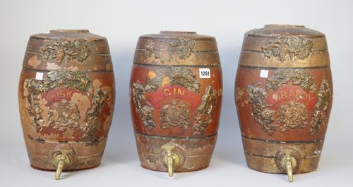 A set of three terracotta spirit barrels, late 19th century, 'Brandy, Whisky and Gin', each relief moulded with fruiting vines and gilt titled against