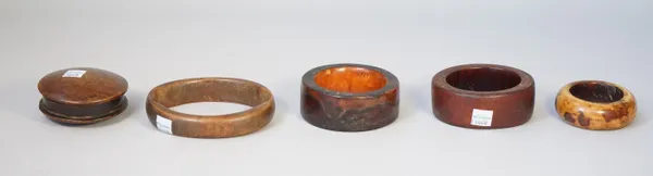 Four late 19th century ivory bangles and a hardwood pot and cover of carved cylindrical form, 8cm diameter, (5).