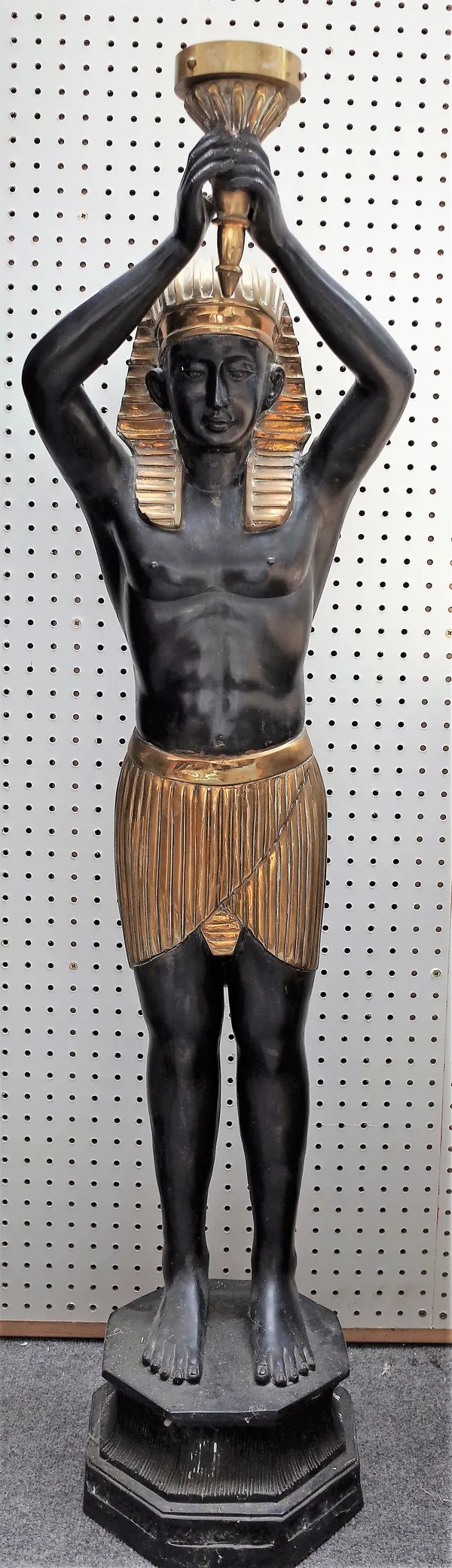 A modern composite bronze figural torchere cast as an Egyptian male carrying a torch, gilt and ebonised, lacking shade, 129cm high.