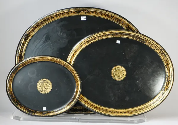 A set of three graduated papier-mâché  oval trays, late 19th century, each with gilt border against an oval ebonised ground, unsigned, on a perspex di