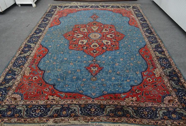 A Tabriz carpet Persian, the indigo field with a bold madder medallion, matching spandrels, all with delicate flower head and sprays, an indigo leaf p