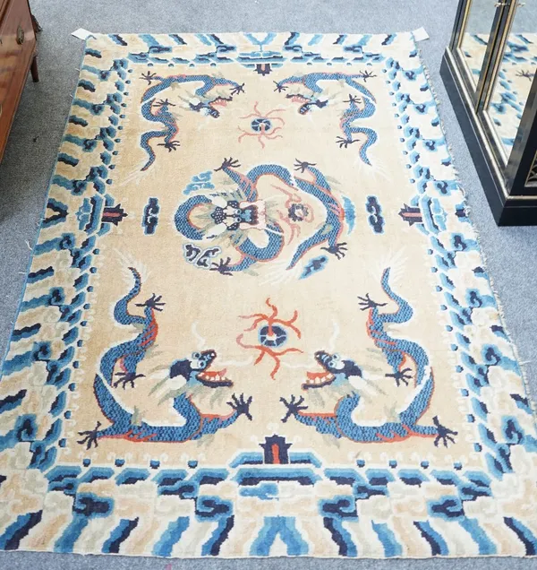 An early 20th century Chinese dragon rug, the beige field with a central indigo dragon, four corner dragons with flaming pearls and a wave border, 195