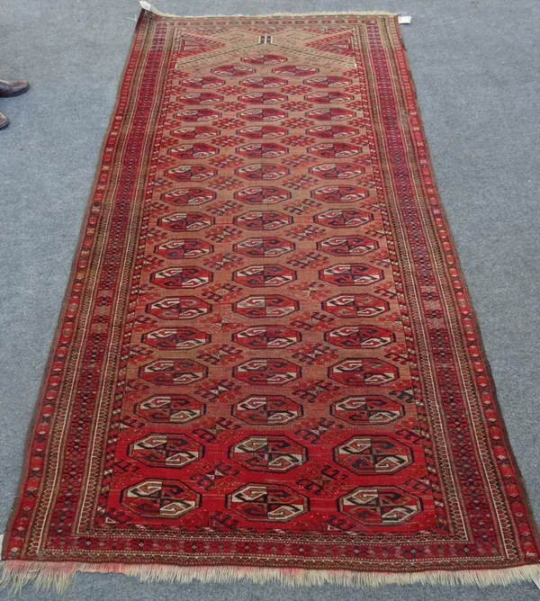 A large Afghan Turkman prayer rug, the madder mehrab with rows of guls, hooked supporting motifs, minor borders, 238cm x 120cm.