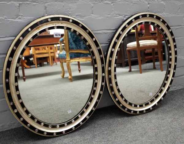 A pair of 19th century Irish ebonised and silvered oval mirrors with hobnail cut glass studded decoration, 52cm wide x 64cm high.