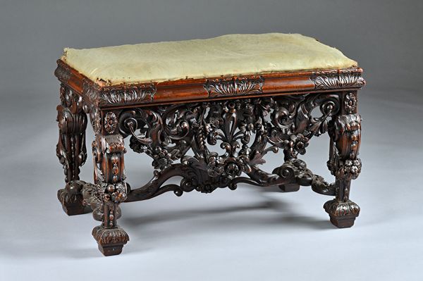 A Baroque revival rectangular stool with extensive carved and pierced frieze united by shaped stretcher, 76cm wide x 50cm high.