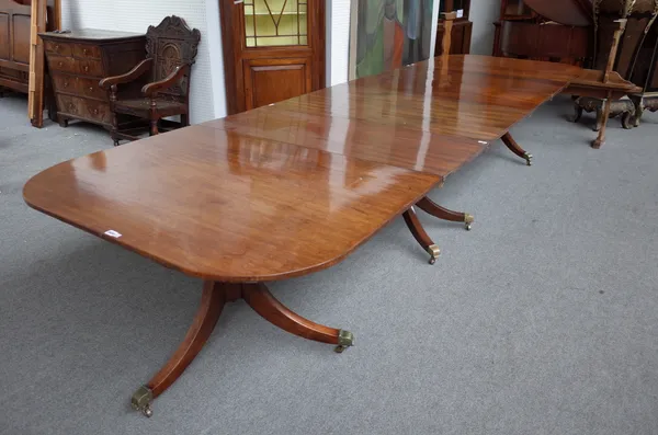 A George III mahogany triple pillar dining table, with ribbed columns on ten downswept supports, with three extra leaves, 124cm wide x 264cm long x 42