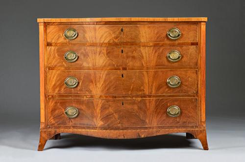 A George III mahogany serpentine chest with four long graduated drawers, the canted corners with satinwood panels, box and ebony stringing, on swept s