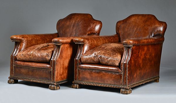 A pair of mid-20th century studded brown leather upholstered easy armchairs on claw and ball feet, 70cm wide x 77xm high.