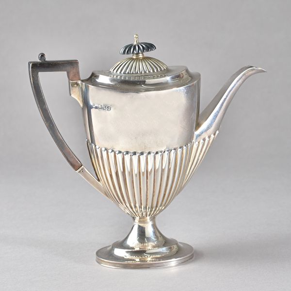 A late Victorian silver coffee pot, of oval form in the Adam style, having partly fluted decoration, raised on an oval foot, with black fittings, Lond