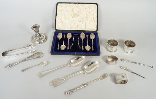 A set of six silver teaspoons and a matching pair of sugar tongs, each with standing figure terminals to the handles and with scrolled decoration to t