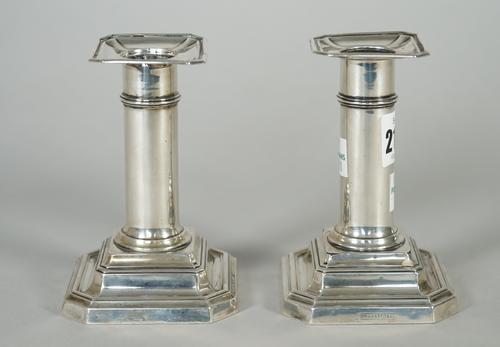 A pair of silver candlesticks, each with a plain column, raised on a cut cornered square stepped base, height 11cm, Sheffield 1905 and a plated hot wa