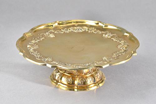 A German silver gilt tazza, on a shaped circular domed foot, chased with rococo scrolls, foliage and fruit, repeated on the detachable top, Dresden ci