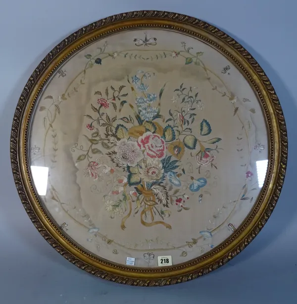 A 19th century circular needlework embroidery depicting a central bouquet of flowers, surrounded by a trailing floral and butterfly border, 64cm diame