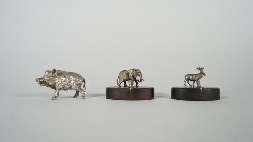 A Patrick Mavros place name card holder, modelled as a standing elephant, raised on an oval wooden base, a Patrick Mavros place name card holder, mode