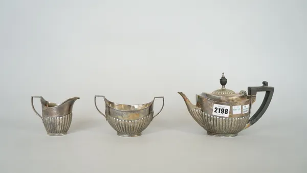 A silver three piece tea set, comprising; a teapot, a twin handled sugar bowl and a milk jug, each piece of oval form, with partly fluted decoration,