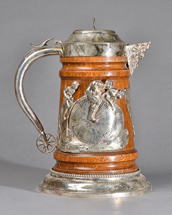 A silver plated metal mounted oak large hinge lidded flagon, the body decorated with cyclists, raised on a circular base, having a beaded rim, the han