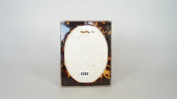 A silver mounted and tortoiseshell rectangular photograph frame, having an oval aperture and with a plain silver border, London 1917, size of frame 22