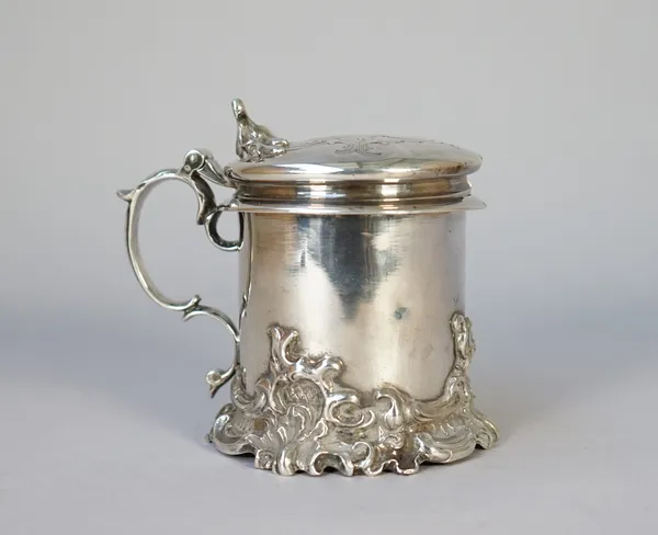 A Victorian silver hinge lidded mustard pot, of cylindrical form, the thumbpiece and the base with cast scrolling decoration, London 1854, maker Charl