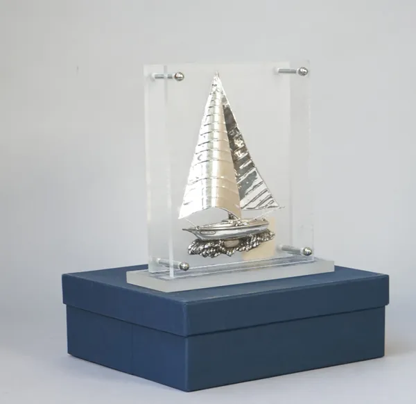 A silver model of a Greek yacht, in sail with rigging, displayed in a perspex stand, detailed Silver, with a box.