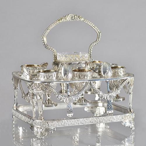 A George III six cup egg cruet frame, decorated with cast swags of oak leaves and acorns and with scallop motifs, fitted with a gadrooned loop shaped