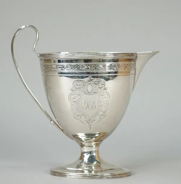 A George III silver milk jug of oval form, with engraved decoration below a reeded band and with a reeded handle, London 1795, weight 140 gms.