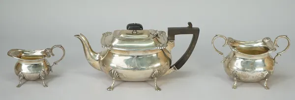 A silver three piece tea set, comprising; a teapot having black fittings, a twin handled sugar bowl and a milk jug, each piece having scallop motifs t
