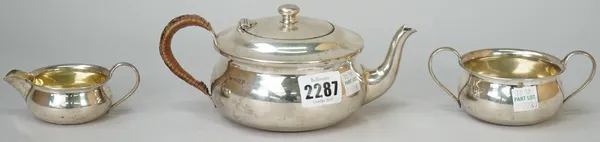 A silver three piece tea set, comprising; a teapot with a rush woven handle, Birmingham 1932, a twin handled sugar bowl, Birmingham 1931 and a milk ju