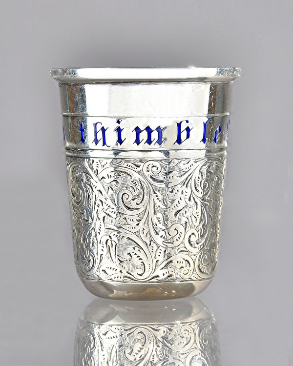 A silver spirit tot, modelled as a thimble, having scroll engraved decoration and detailed in blue enamel 'Just a thimbleful', Birmingham 1900, height