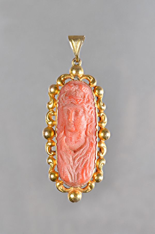 A gold mounted coral pendant, as converted from a clasp, carved as the figure of a lady within a beaded and scrolling surround, gross weight 9.2 gms.