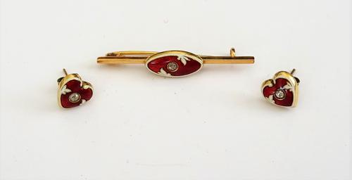 A gold, enamelled and diamond set bar brooch, the oval centre mounted with a cushion shaped diamond, on a red and white enamelled ground and a pair of
