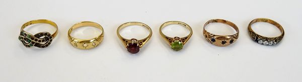 A 9ct gold ring, claw set with a circular cut peridot, a 9ct gold ring, claw set with a circular cut garnet, a gold ring, mounted with four cushion sh