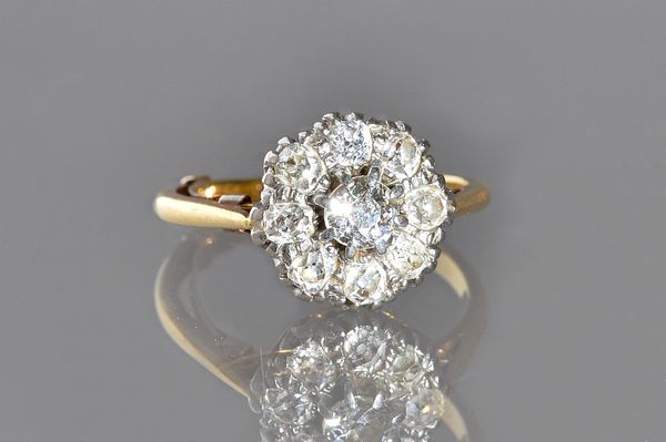 A gold and platinum, diamond set nine stone cluster ring, claw set with the principal cushion shaped diamond to the centre, in a surround of eight sma