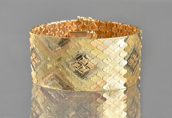 A three colour gold bracelet, in a wide shaped link design, with partly facet cut decoration, detailed 750, on a snap clasp, with foldover safety catc