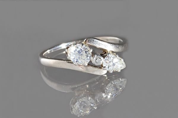 A diamond ring, claw set with two principal pear shaped diamonds and with a small cushion shaped diamond, in a crossover design, ring size P, gross we