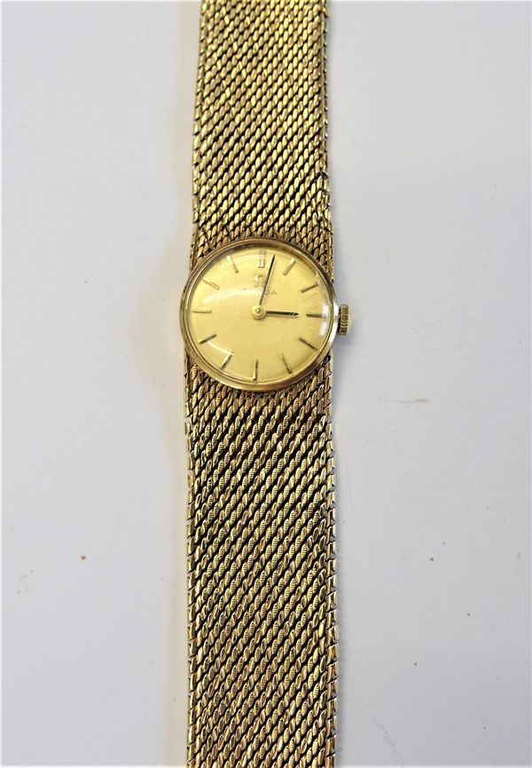 An Omega 9ct gold lady's bracelet wristwatch, the signed gilt dial, with gilt baton numerals and with black hands, on a woven mesh link bracelet, with